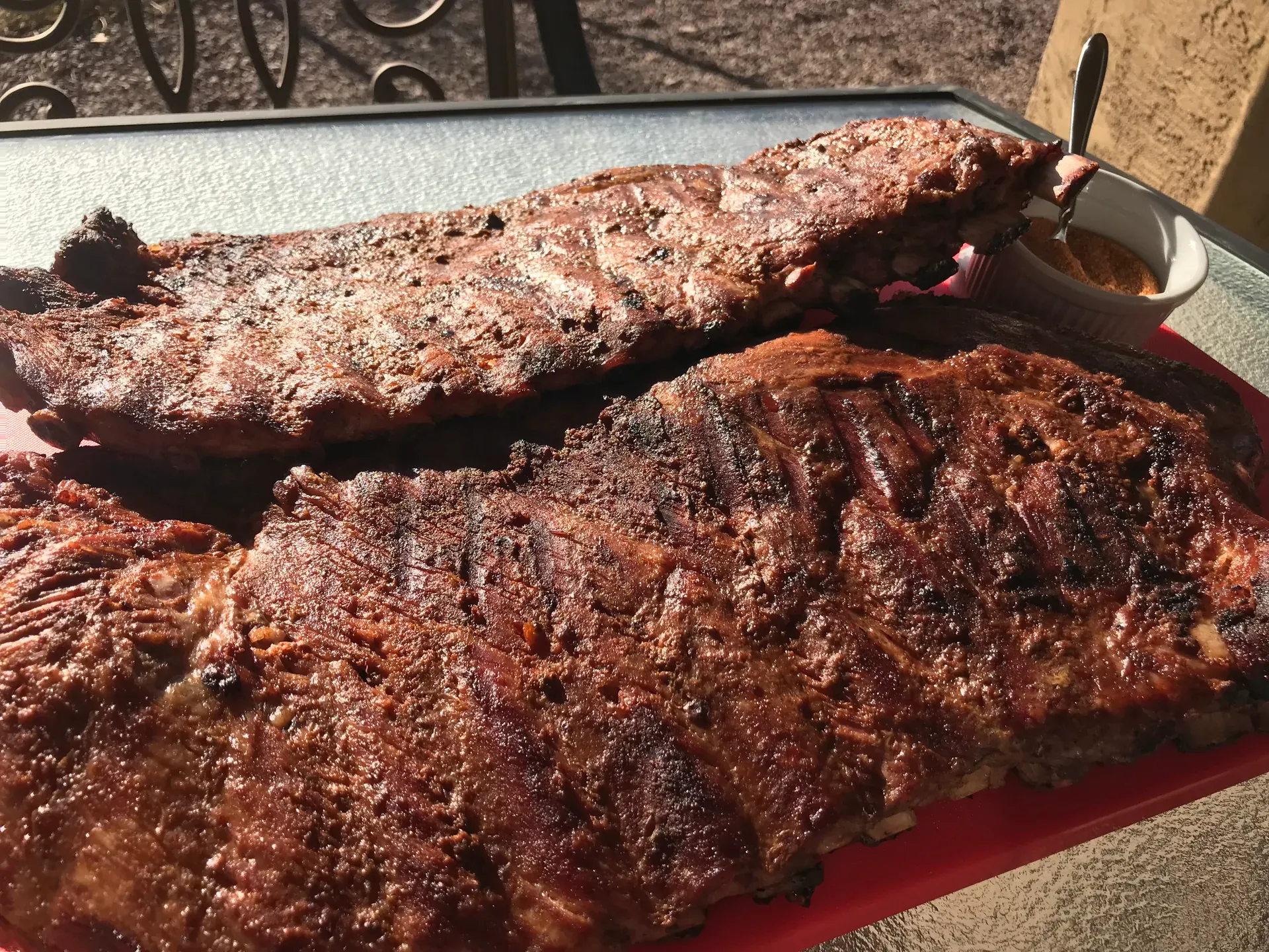 Two slabs of slow-smoked baby back ribs from The Pitmaster’s Secret on a red serving platter