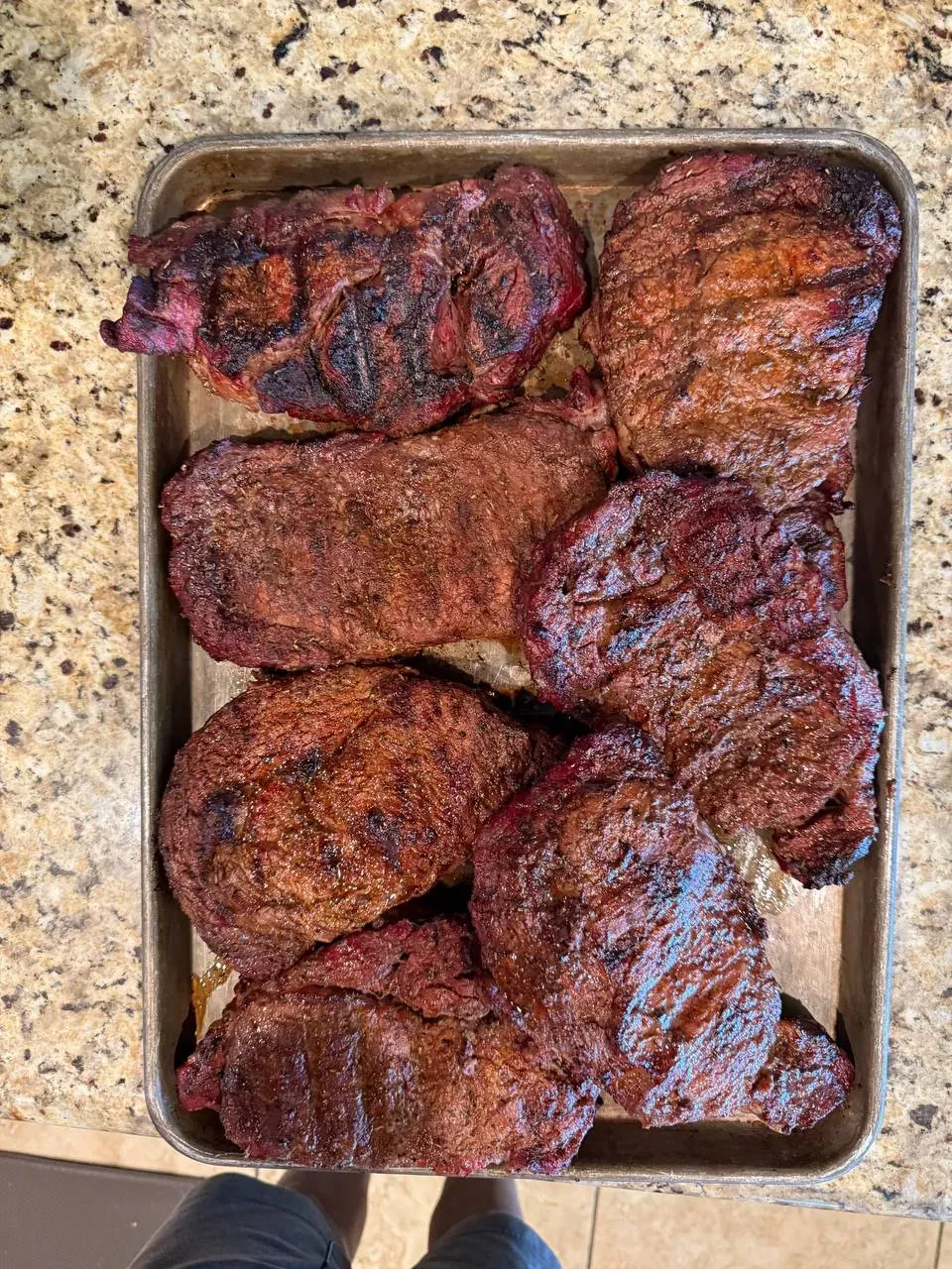 Sheet pan loaded with smoked brisket pieces fresh off the pit, ready for catering trays
