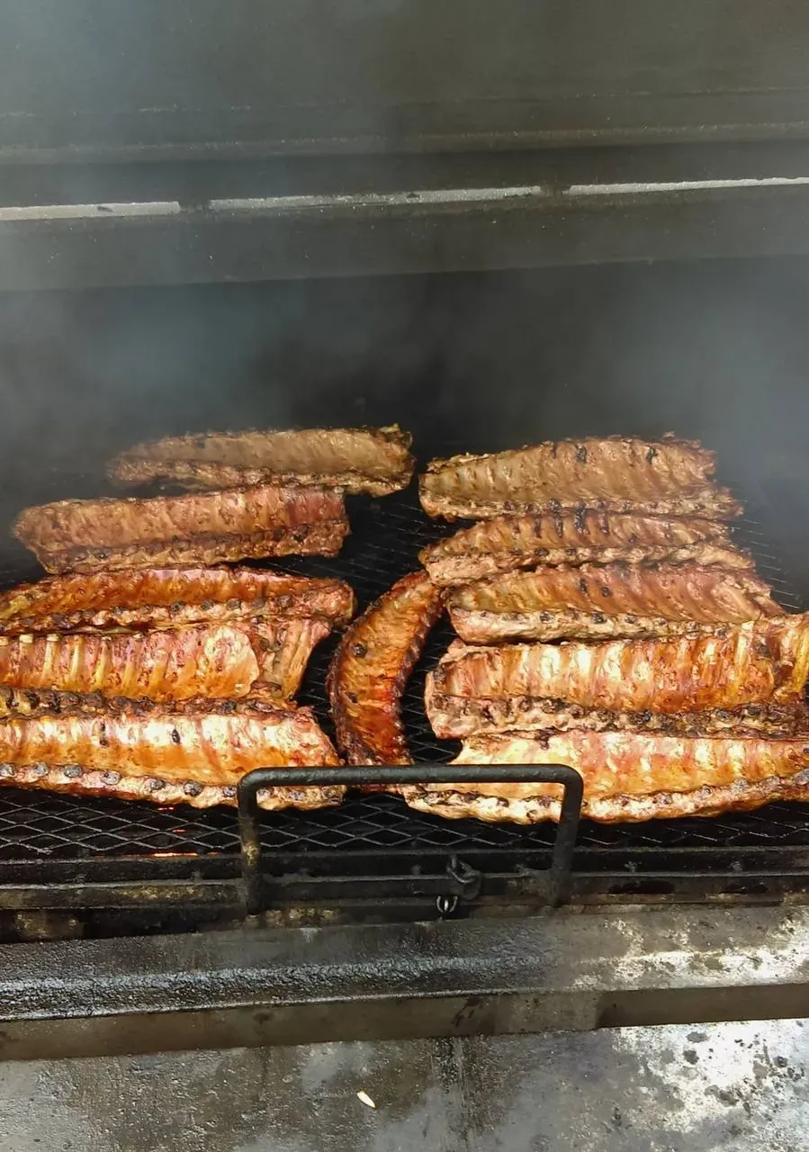 Multiple racks of baby back ribs slow-smoking on the Pitmaster’s Secret pit in Phoenix