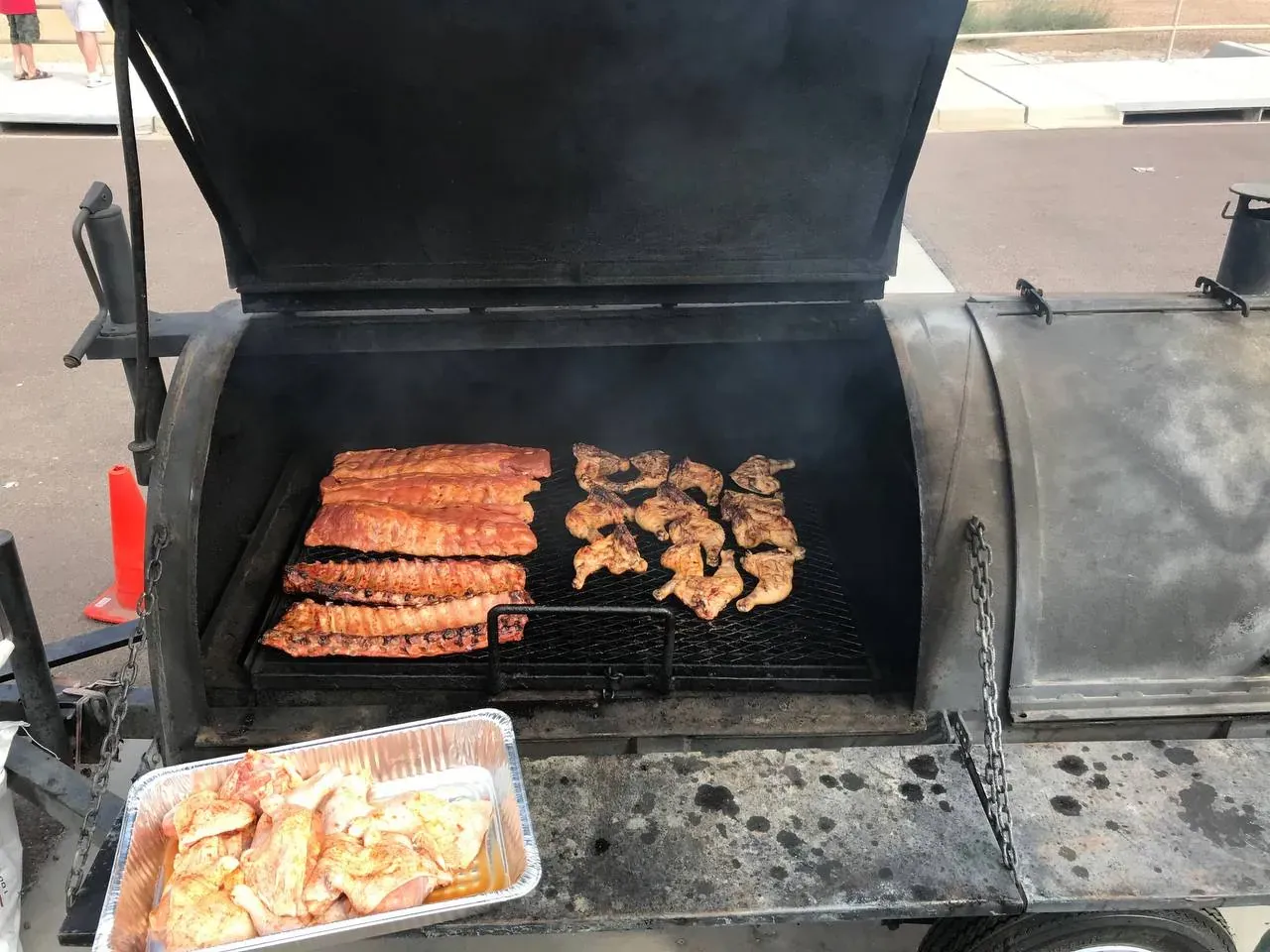 Slow-smoked BBQ being served from foil pans at a community gathering in the Valley