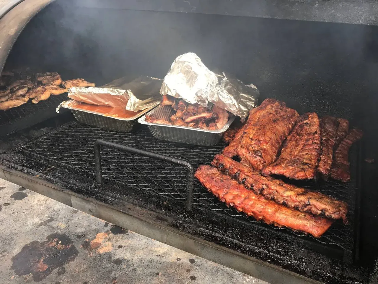 Racks of ribs, brisket, and sausage smoking together on The Pitmaster's Secret trailer pit in Arizona